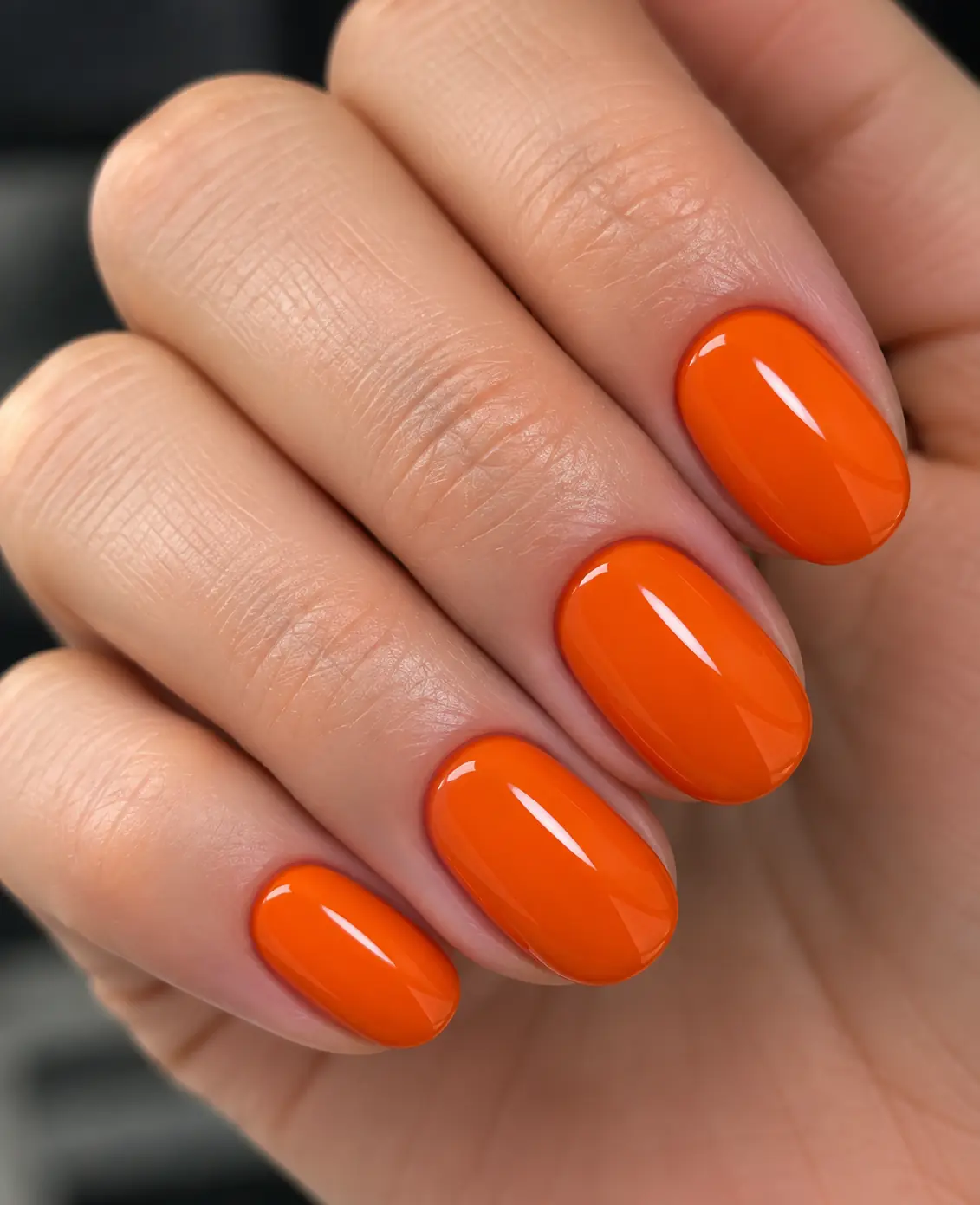Bright glossy orange manicure on short rounded nails