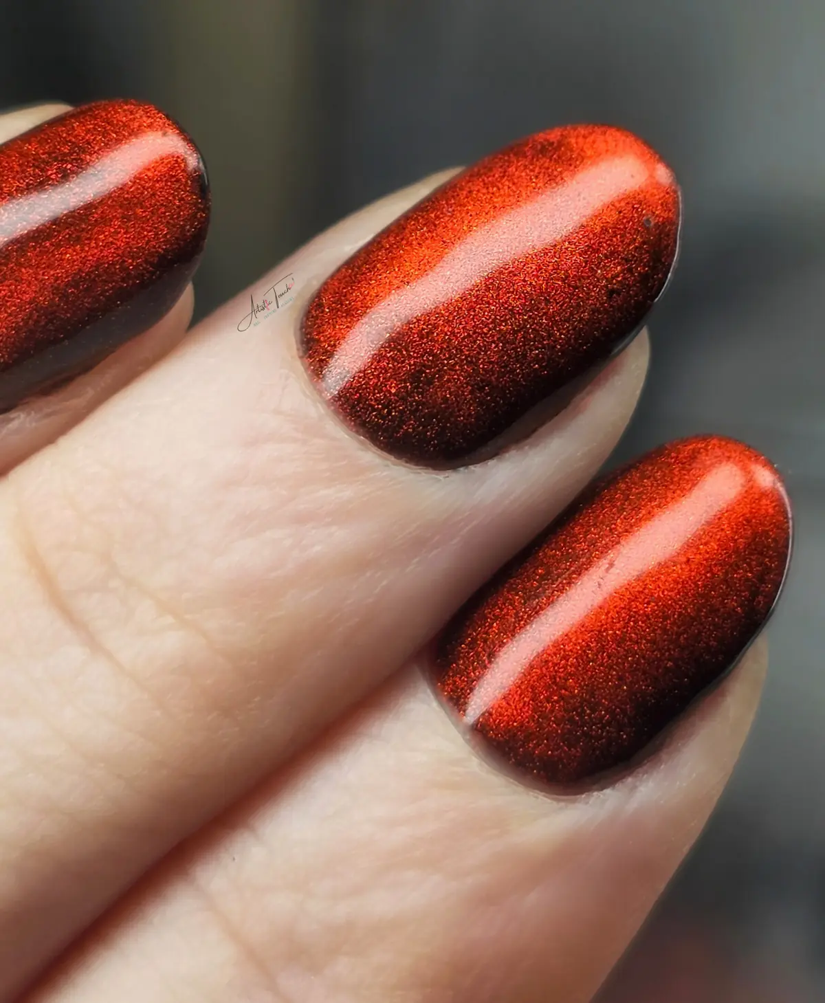 Deep red magnetic cat-eye manicure with a copper shimmer and a band of light across each nail
