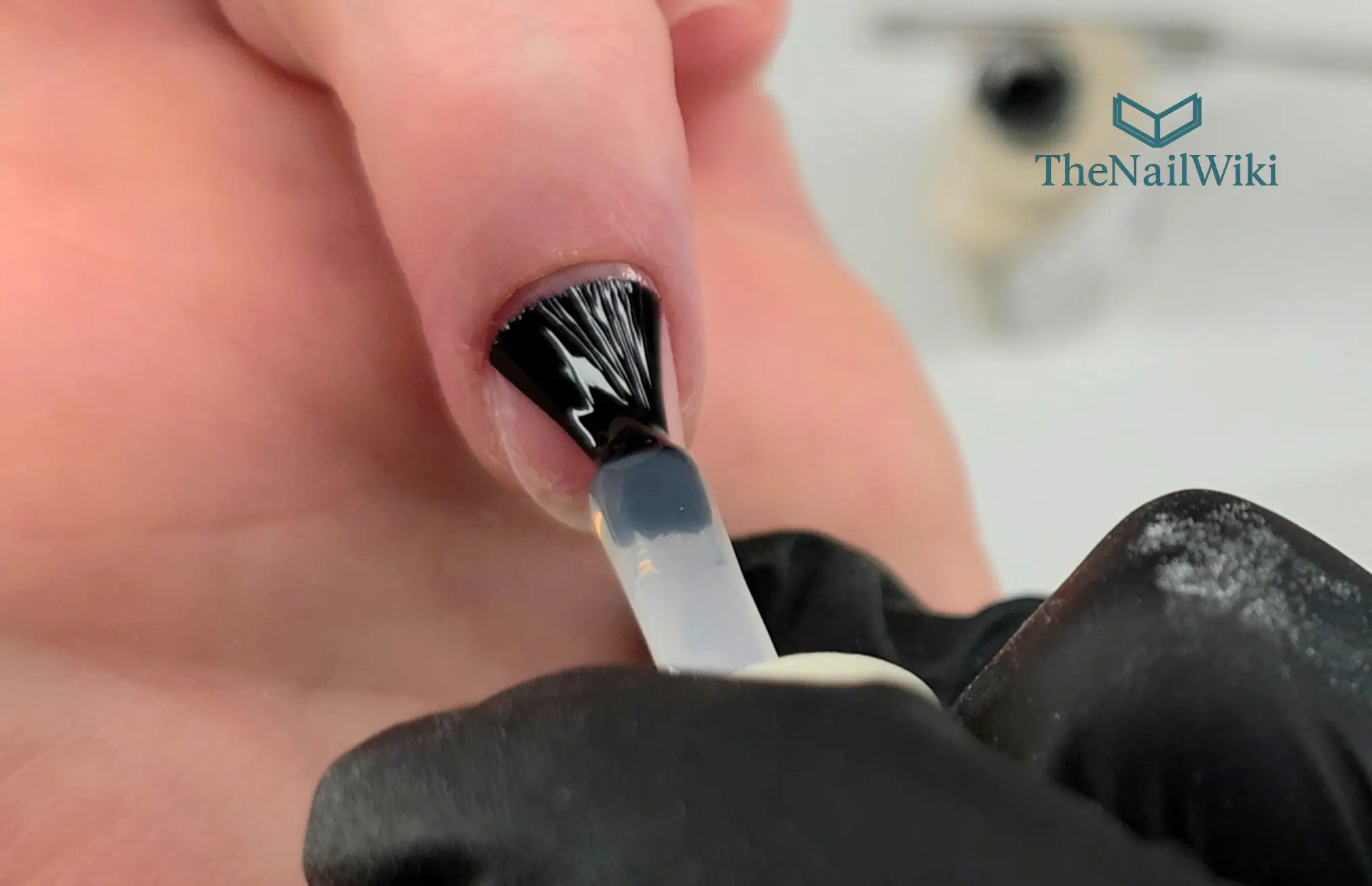 Rubber base coat being applied to a natural nail using small rubbing motions — working the product into the nail plate surface for full even coverage